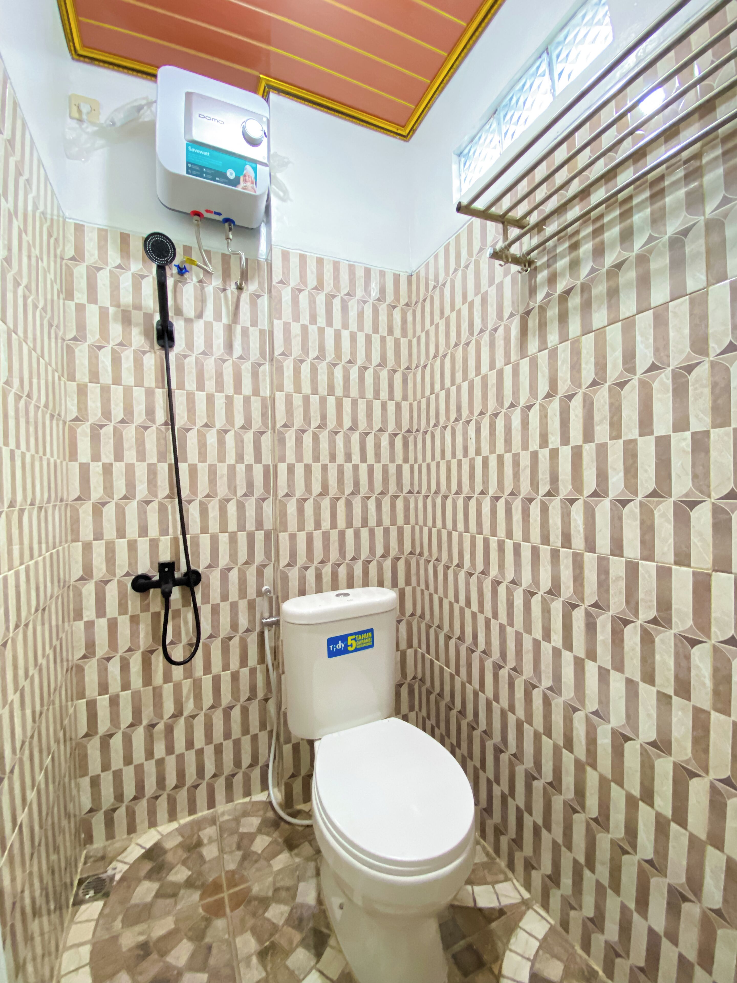 Un baño con piso de baldosas a cuadros, un inodoro y un cabezal de ducha en la pared.