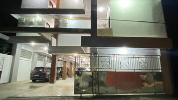 A multi-story building with a gated entrance and a car parked inside.