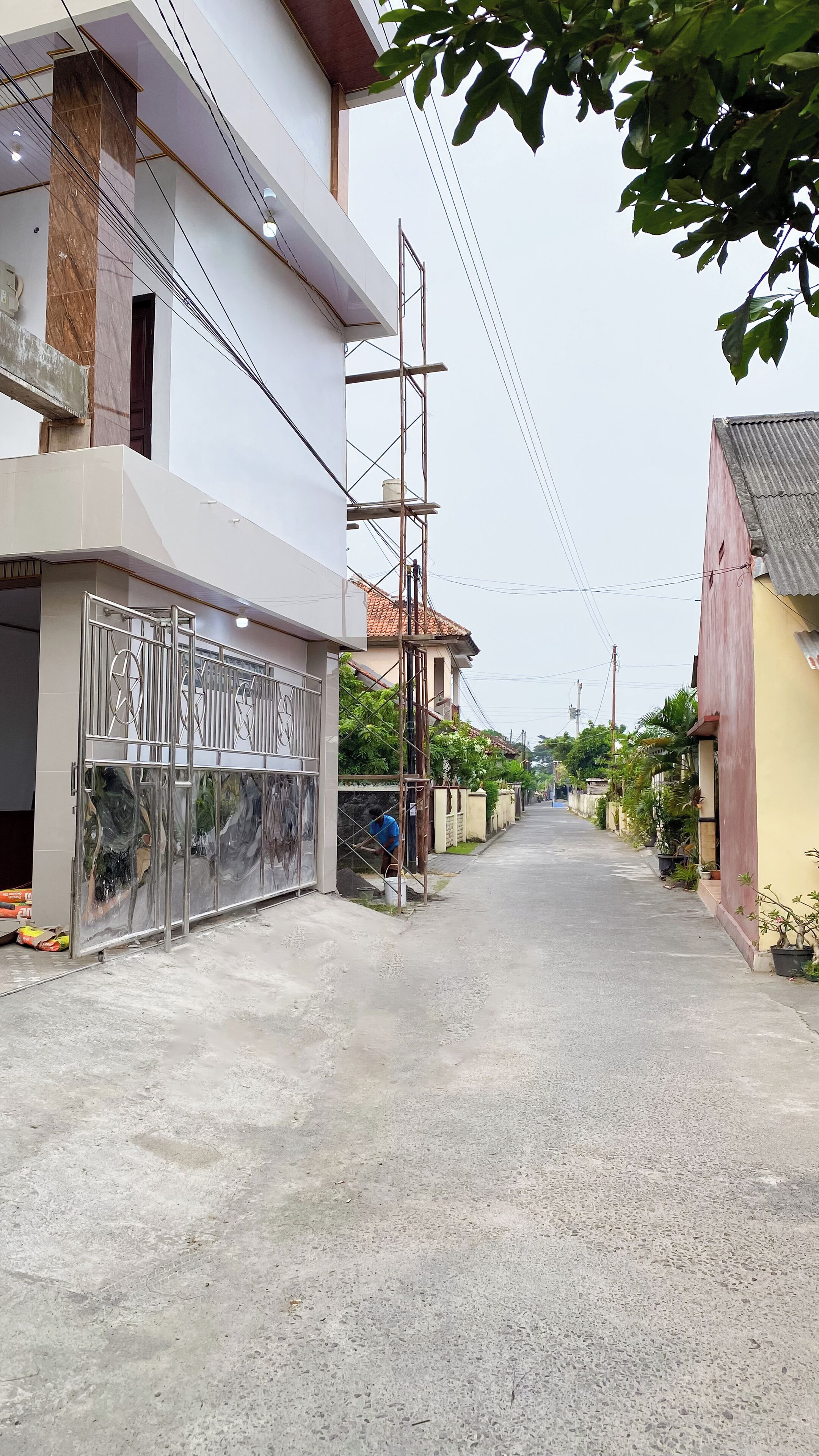 A residential street with houses on either side, a gated entrance, and a clear sky.