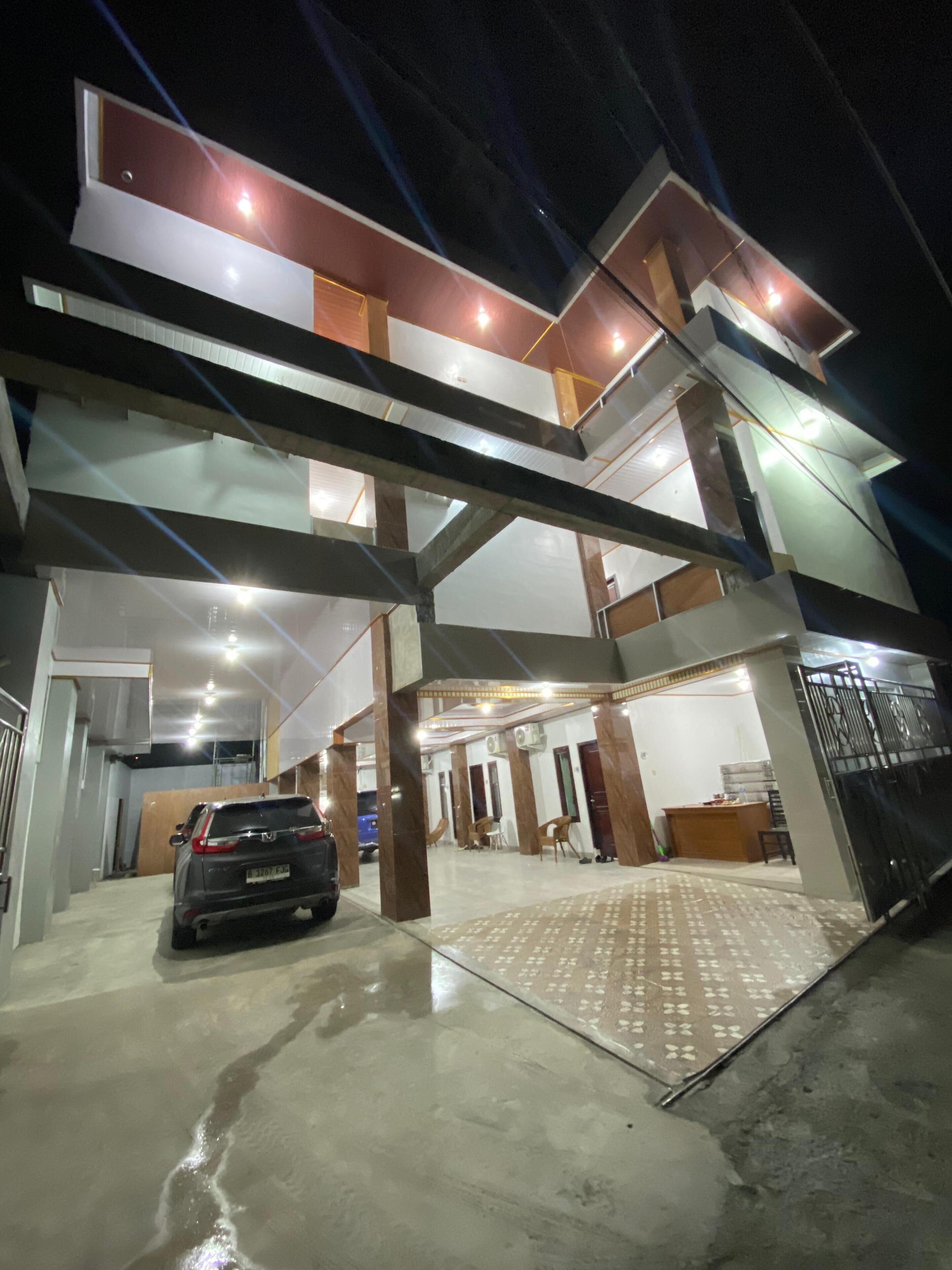A multi-level building with a car parked in the driveway.