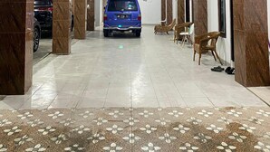 A parking garage with a blue car, tiled floors, and a ceiling with recessed lighting. - d'WF Hotel (Kalasan)