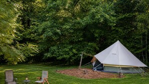 A tent set up in a grassy area with a fire pit and two chairs. - Boho Off-grid Glamping at Honeysuckle Springs (Cosby)