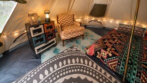 A tent interior with a bed, a chair, a dresser, and a lantern. - Boho Off-grid Glamping at Honeysuckle Springs (Cosby)