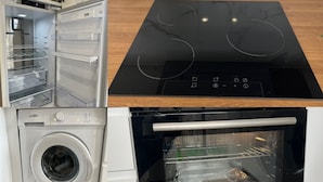 Une cuisine équipée d’un four à micro-ondes encastré, d’une plaque de cuisson à induction noire, d’un four encastré et d’un lave-linge.