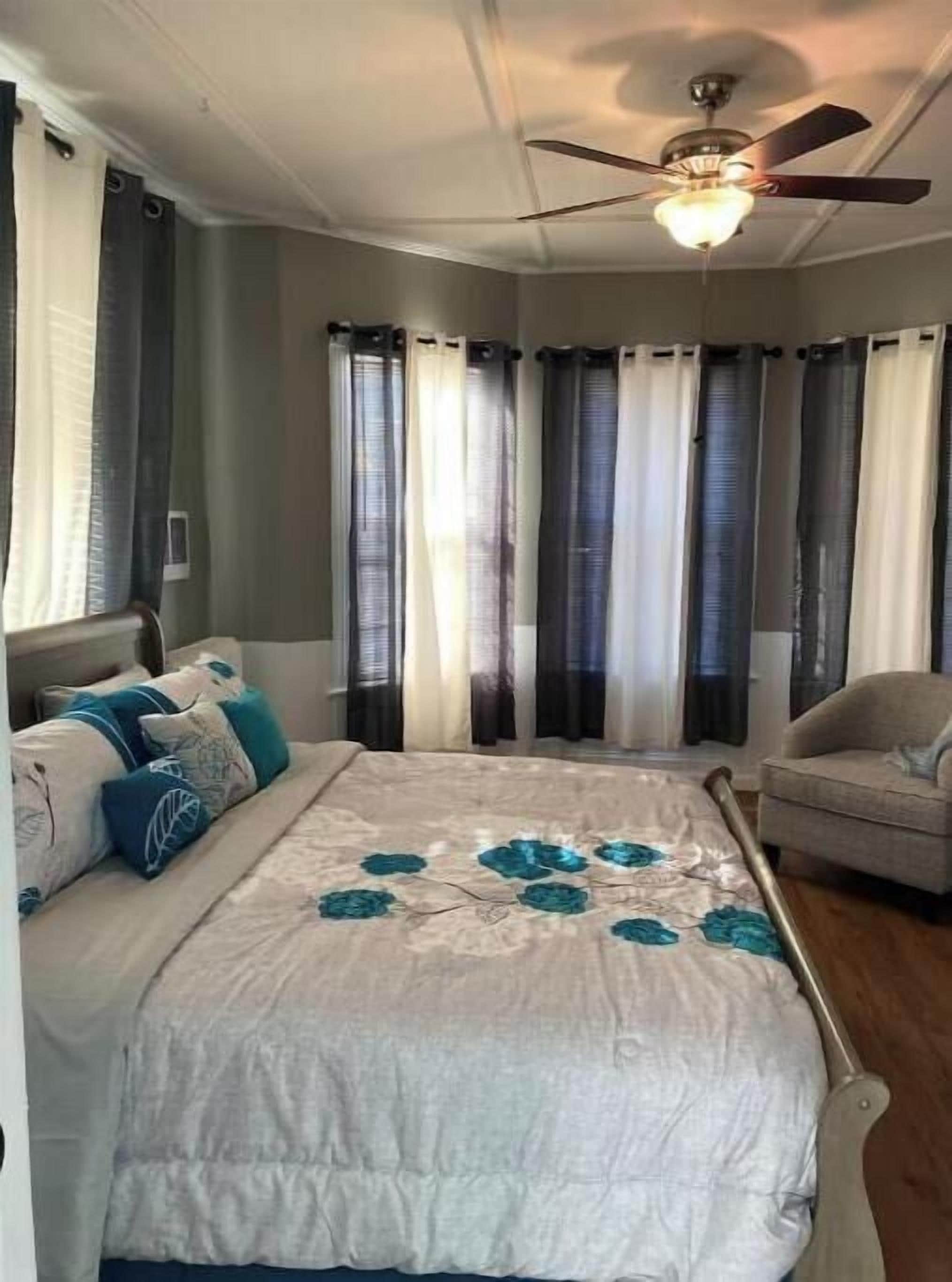 A bedroom with a bed, a ceiling fan, and curtains.