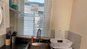 Uma cozinha com pia de aço inoxidável, torneira, suporte para facas e escorredor de louça.