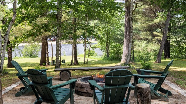 A lakeside campsite with green Adirondack chairs, a fire pit, and a picnic table. - Waterfront retreat with fireplace 3 miles from Whiteface & The North Pole (Wilmington)