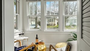 Una habitación acogedora con un ventanal grande, una mesa con una botella y vasos, y un espacio de descanso confortable.