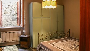 A bedroom with a bed, a wardrobe, a radiator, a window with shutters, and a hanging lamp. - Brothers Home: Italian Vacation (Civitella Casanova)