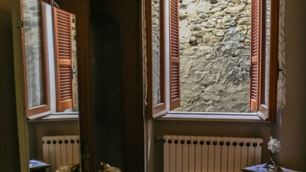 A bathroom with a glass vanity, a mirror, a radiator, and a window with shutters. - Brothers Home: Italian Vacation (Civitella Casanova)