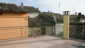 A rooftop terrace with stone walls and tiled roofs, featuring a metal railing and a satellite dish. - Brothers Home: Italian Vacation (Civitella Casanova)