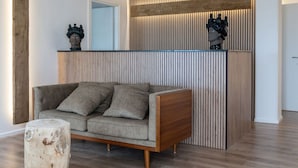 A modern living room with a grey sofa, a wooden coffee table, and a decorative wall panel.