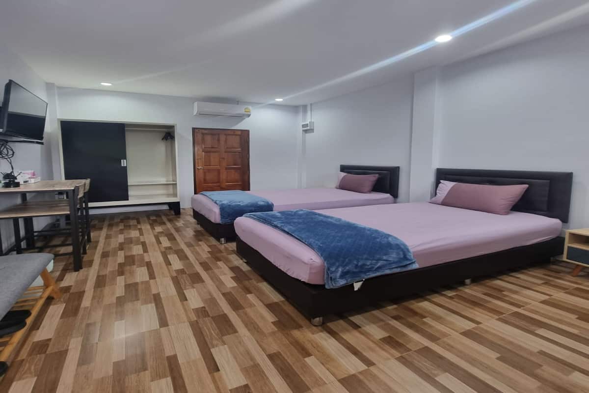 A bedroom with two beds, a desk, and a wardrobe.