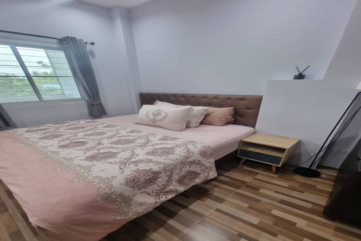 A bedroom with a bed, a nightstand, a lamp, and a window with curtains.