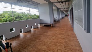 A corridor with large windows, wooden flooring, and a bench. - Patamanan Residence Ang Thong (Wiset Chai Chan)