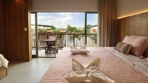Ein Hotelzimmer mit einem großen Bett, einem Balkon mit Tisch und Stühlen und Blick ins Freie.