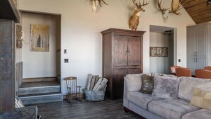 A rustic interior with a wooden staircase, a gray sofa, and antlers mounted on the ceiling. - Modern Cabin at Blue Mesa, INCREDIBLE VIEWS, 40min from BLK CNYN (Gunnison)