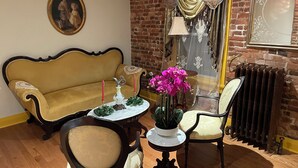 A room with a yellow sofa, a wooden chair, a small table with a vase of flowers, and a radiator. - Step back in time and experience the elegance of Victorian era.  (Reading)