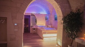 Une salle de spa dotée d’une arche en pierre, d’une baignoire et d’un petit coin salon.