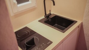 Une petite cuisine équipée comprenant un four à micro-ondes encastré, un évier et une fenêtre située au-dessus de l’évier.