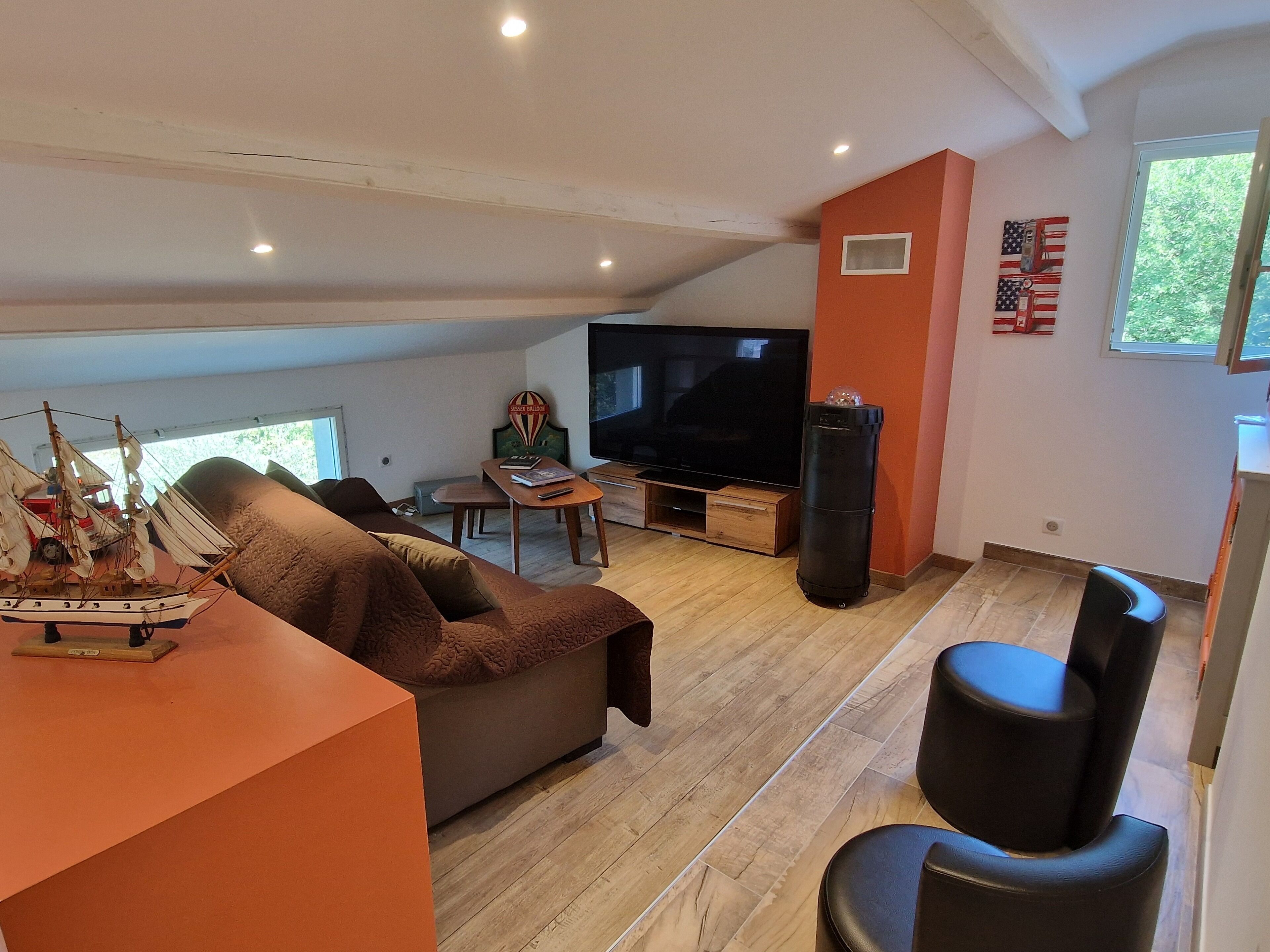 Una sala de estar con un sofá, una mesa de centro, un televisor y un modelo de barco.