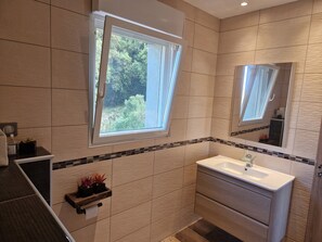 Un baño moderno con un amplio ventanal, un lavabo y un espejo.
