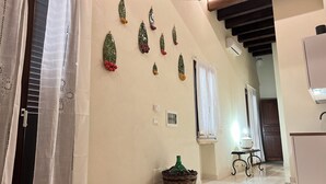 Un pasillo con suelo de baldosas, una cesta de mimbre con una botella verde y una pared con detalles decorativos.