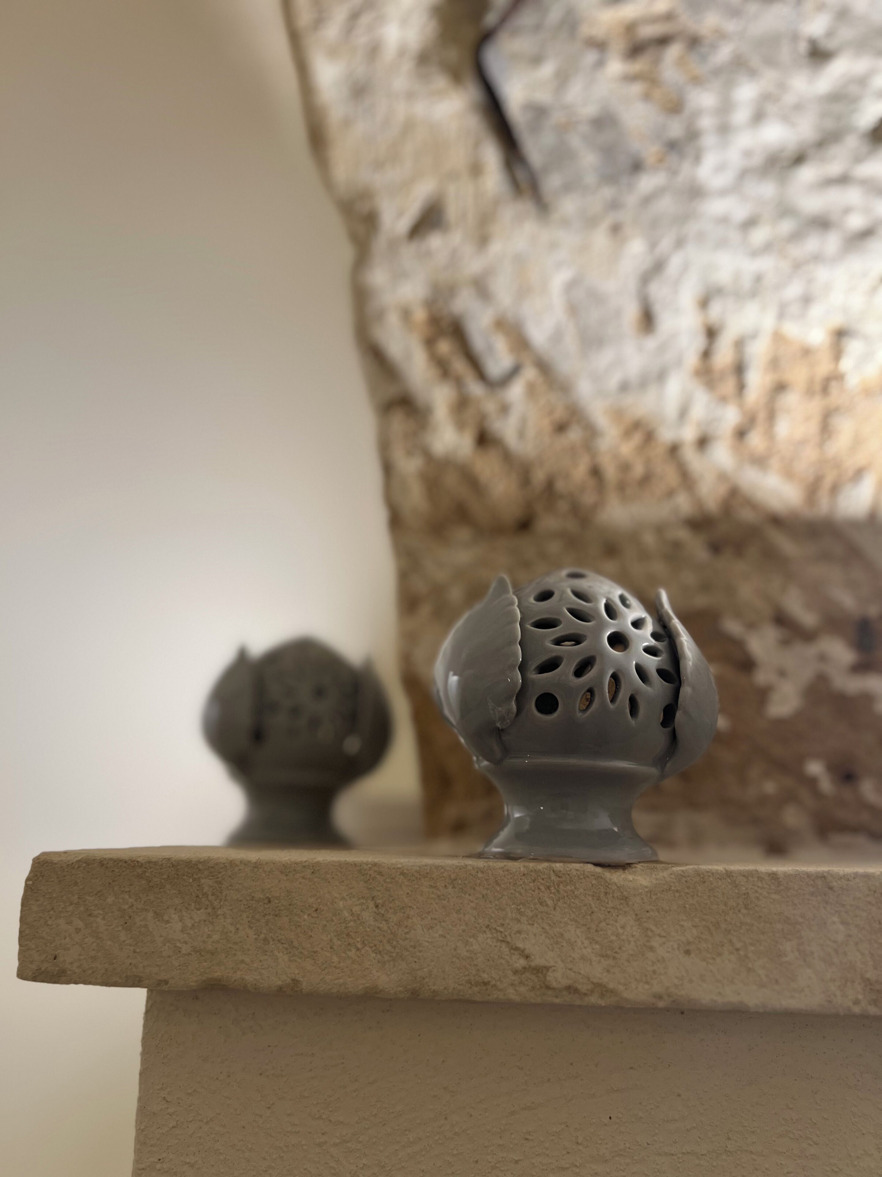 Una pared de piedra con superficie rugosa y un objeto pequeño y redondo de color gris encima.