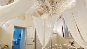Un dormitorio con una cama, cortinas blancas y un techo con diseño floral.