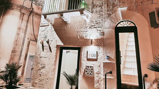 Un edificio de varios pisos con balcones, una puerta con el rótulo 