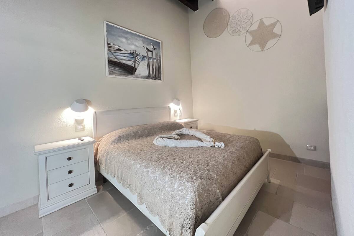 Une chambre à coucher avec un lit, deux tables de chevet, une commode, une lampe et un tableau au mur.
