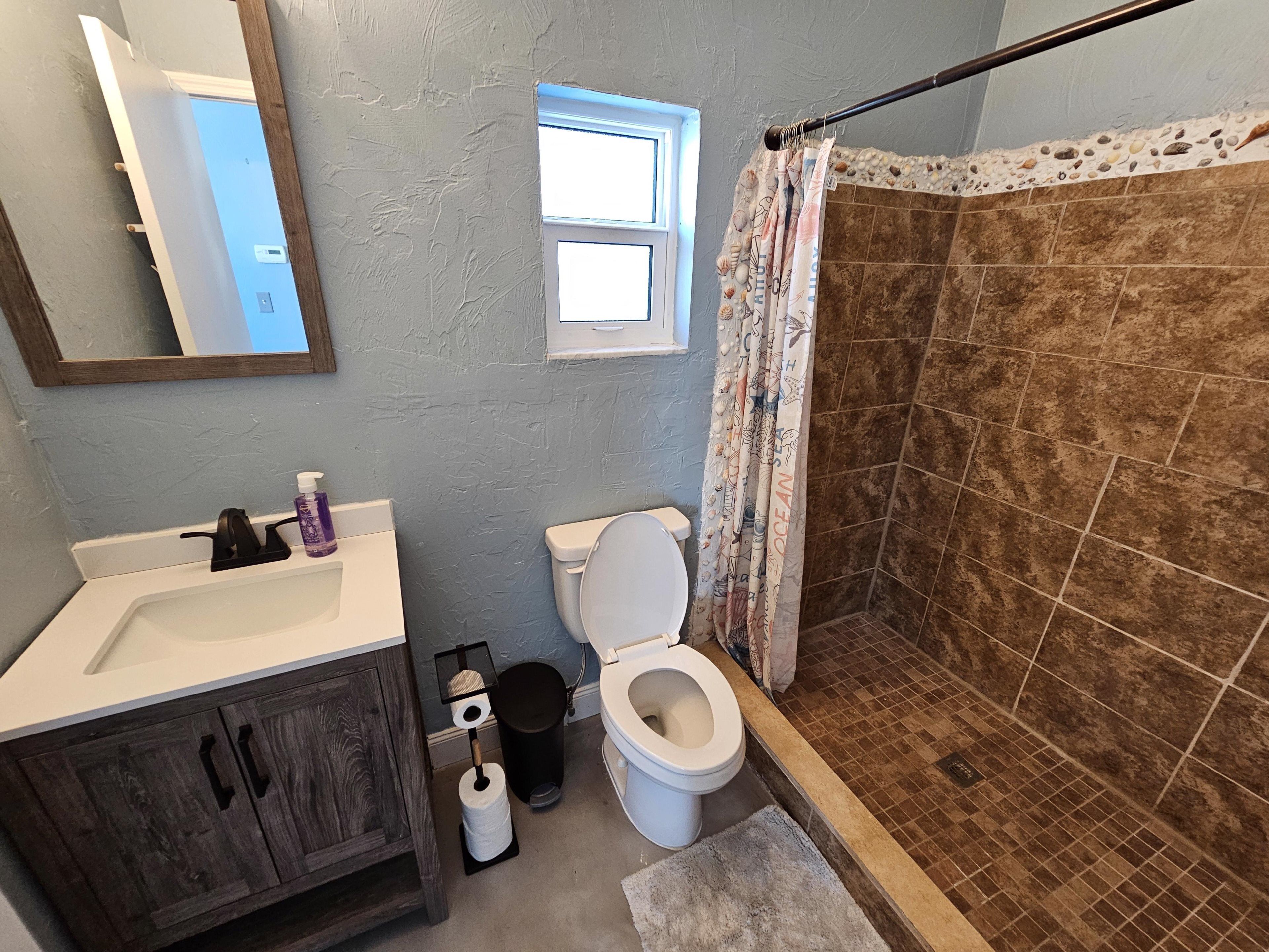Ein Badezimmer mit Dusche, Toilette, Waschbecken und Spiegel.