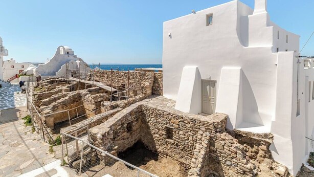 A white building with a stone courtyard, a small window, and a clear blue sky.