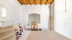 A bedroom with a bed, a dresser, a mirror, and a wardrobe.