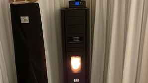 Une pièce avec un radiateur noir, des rideaux blancs et un canapé gris.