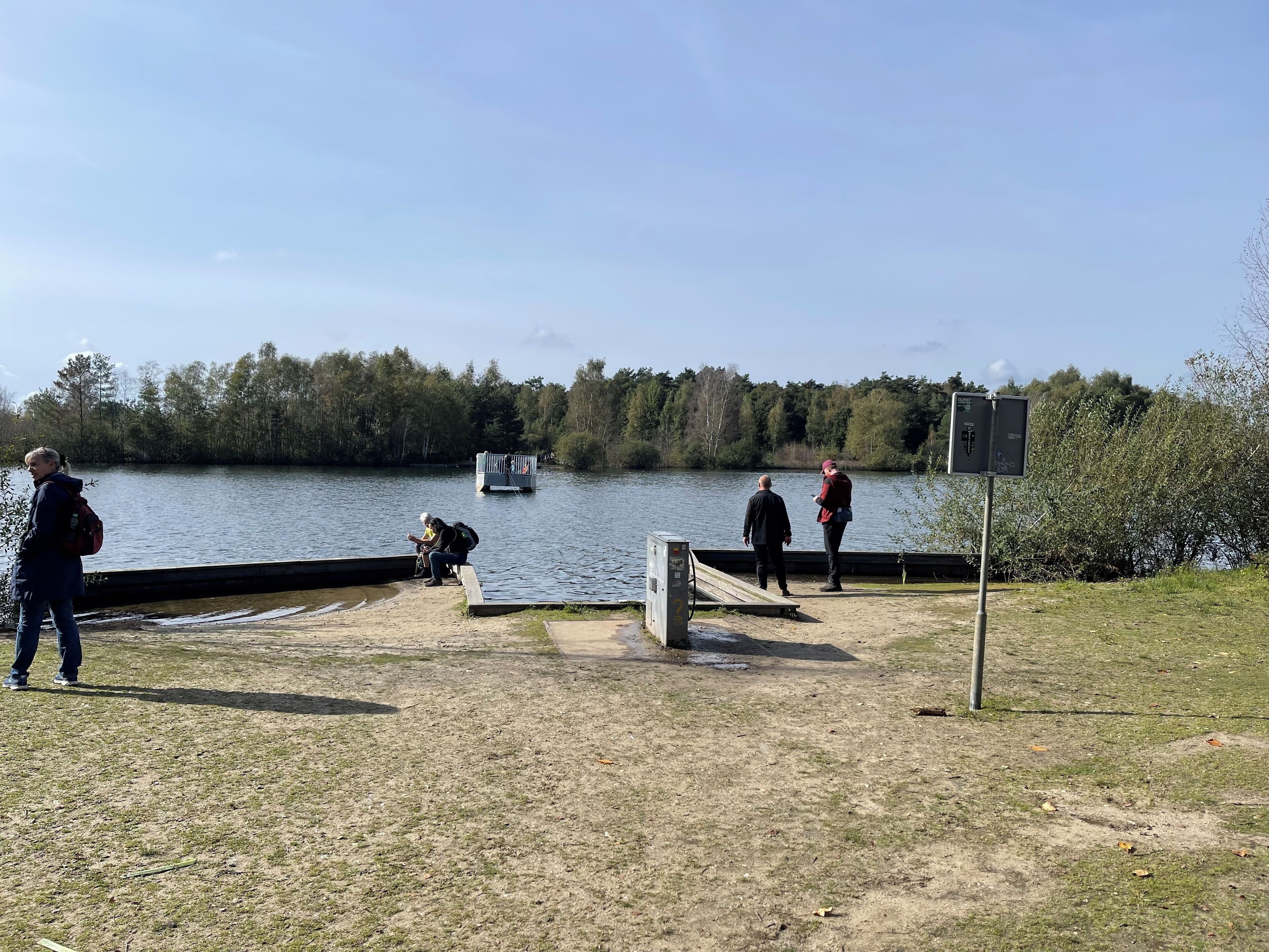 Une zone au bord du lac, avec un quai, un bateau et un panneau indicateur.