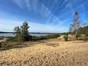 A sandy beach with sparse vegetation and a clear view of a lake. - Chalet im Ferienpark, Irrlandpark, Maasdünen, Naturerlebnis, Kinderfreundlich (Wellerlooi)