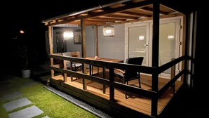 Une terrasse extérieure couverte, dotée d’une rambarde en bois, d’une table à manger et de chaises.