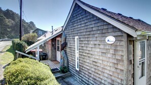 A wooden building with a sloped roof, a small porch, and a door with a window. - Haystack Haven-Haystack Rock View-Sunset Views-Popular Destination-Unwind (Cannon Beach)