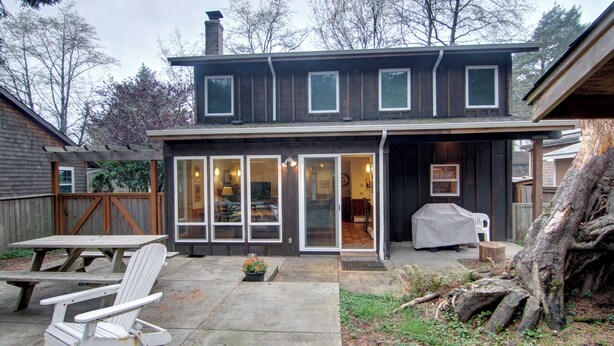 A two-story house with a covered patio area, a sliding glass door entrance, and a barbecue setup. - Sea Pines -dog friendly-Spacious and family Friendly-Secluded (Cannon Beach)
