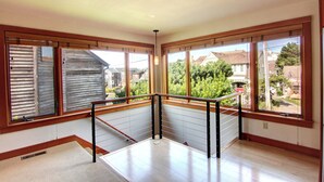 A corner room with large windows, a wooden floor, and a metal railing. - Koblegarde's Beach House-Unwind and recharge-Fireplace & Cozy Vibes-Peaceful (Cannon Beach)