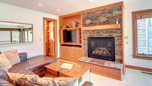 A living room with a stone fireplace, wooden shelves, a television, and a sofa. - Koblegarde's Beach House-Unwind and recharge-Fireplace & Cozy Vibes-Peaceful (Cannon Beach)