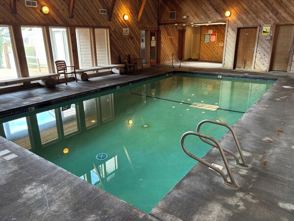 An indoor swimming pool with wooden walls, a bench, and a lifeguard chair. - Sandcastle condo C-1- Indoor Pool- Family/Pet Friendly-Family Getaway (Cannon Beach)