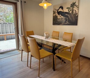 Un coin repas avec une table en verre, des chaises jaunes, un petit objet décoratif et un tableau accroché au mur.
