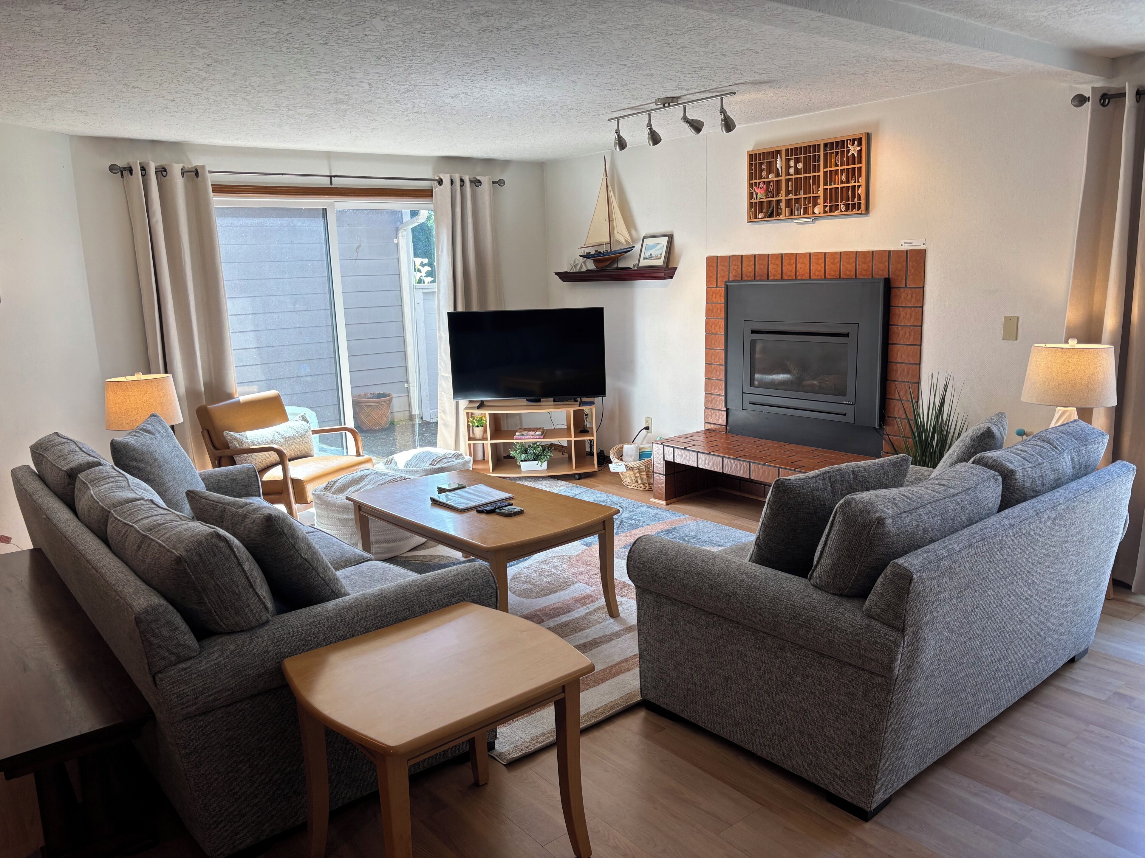Uma sala de estar com sofá, mesa de centro, televisão, lareira e janela com cortinas.