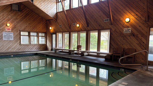 Una piscina interior con paredes de madera, bancos y una silla para socorrista.