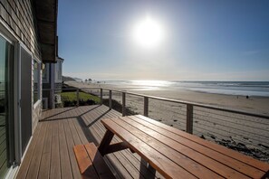 Une terrasse en bois avec un banc donnant sur une plage.