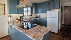Una cucina con mobili blu, un piano di lavoro in granito, elettrodomestici in acciaio inossidabile e un forno integrato.