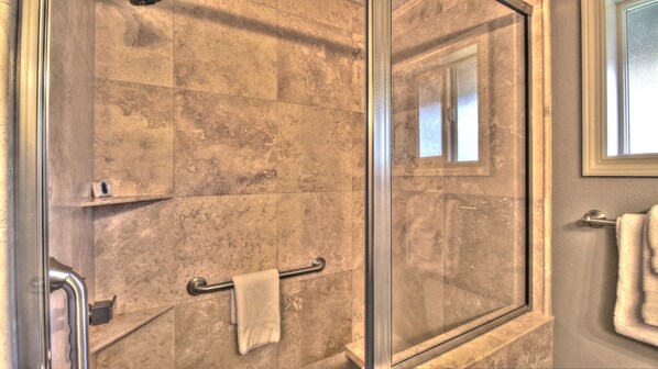 A shower area with a glass door, a towel rack, and a small shelf.