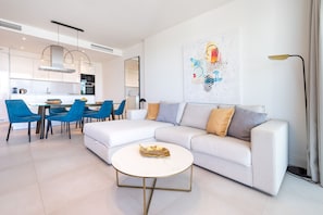 A modern living room with a white sofa, blue chairs, and a round coffee table.